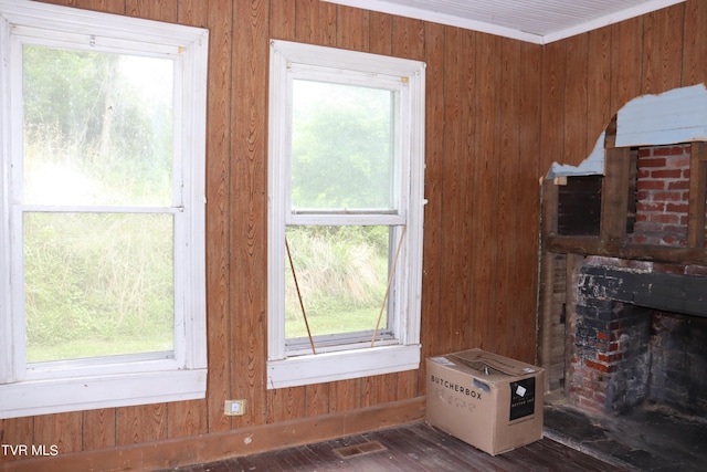 living room with wood walls, ornamental molding, a fireplace, and dark wood-type flooring