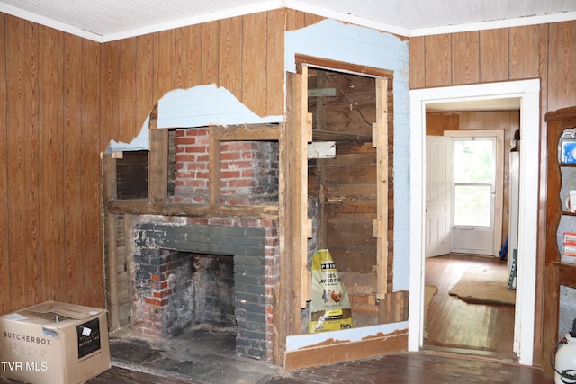 unfurnished living room featuring a fireplace, crown molding, and wood walls