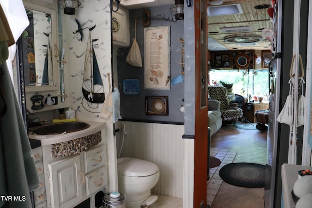 bathroom featuring wooden walls, vanity, and toilet