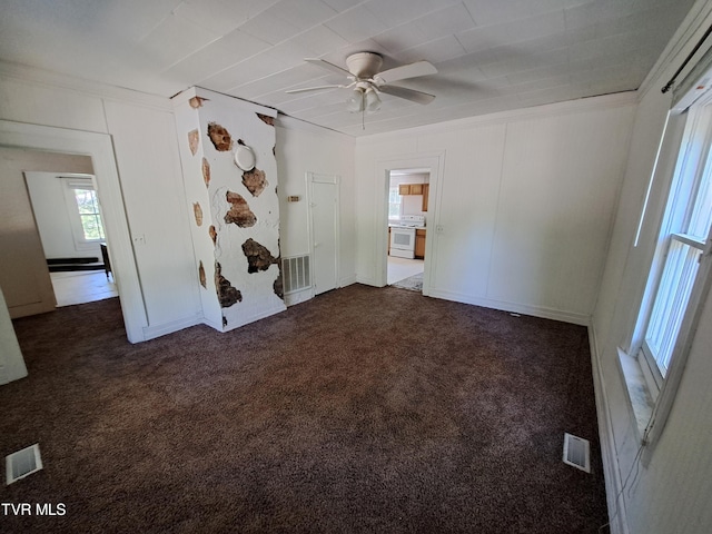 spare room featuring dark colored carpet, ceiling fan, and crown molding