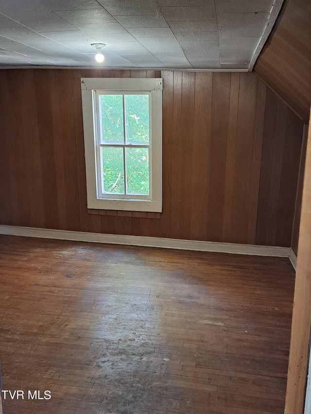 additional living space with lofted ceiling, wood walls, and dark hardwood / wood-style floors