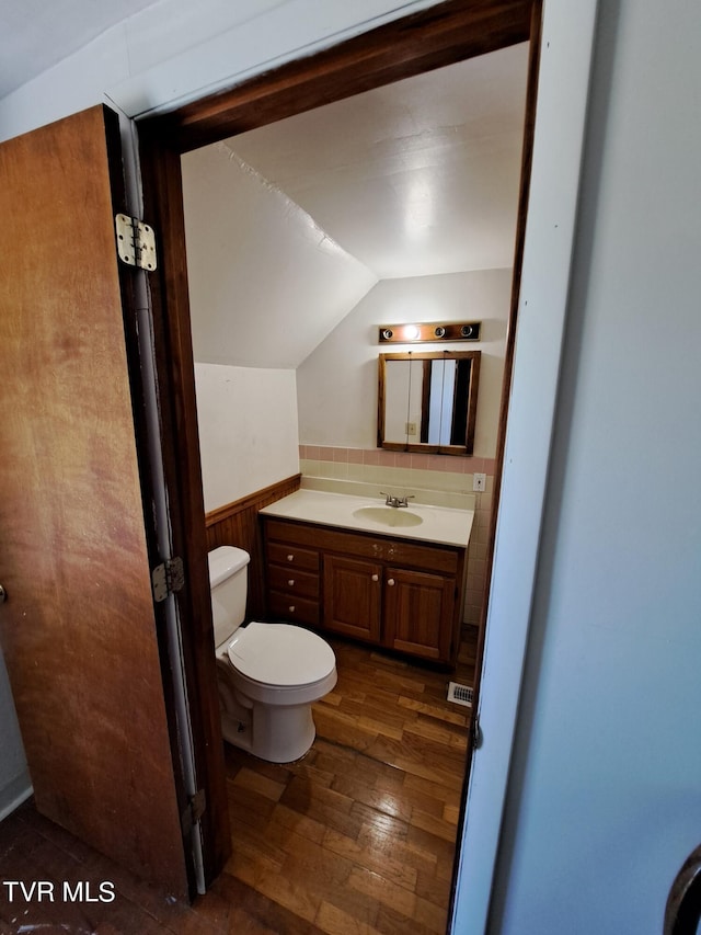 bathroom featuring hardwood / wood-style flooring, vanity, toilet, and vaulted ceiling