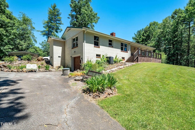 view of front facade featuring central AC, a garage, and a front lawn