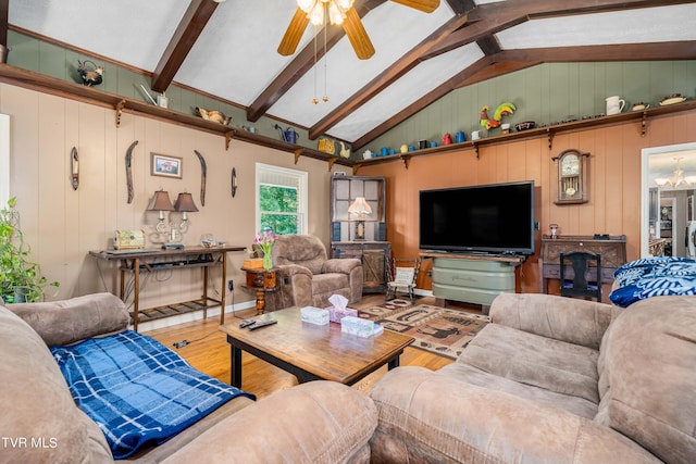 living room featuring ceiling fan with notable chandelier, vaulted ceiling with beams, hardwood / wood-style flooring, and wooden walls