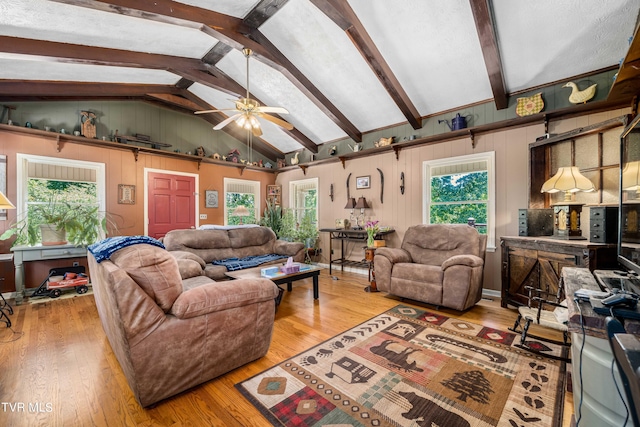 living room featuring hardwood / wood-style floors, vaulted ceiling with beams, ceiling fan, and a wealth of natural light