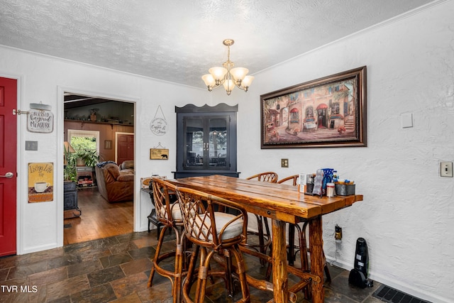 dining room with a chandelier, a textured ceiling, and ornamental molding