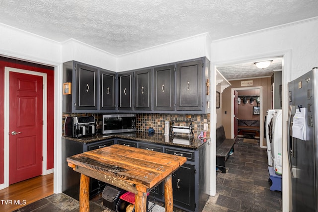 kitchen with stainless steel appliances, backsplash, dark stone counters, a textured ceiling, and ornamental molding