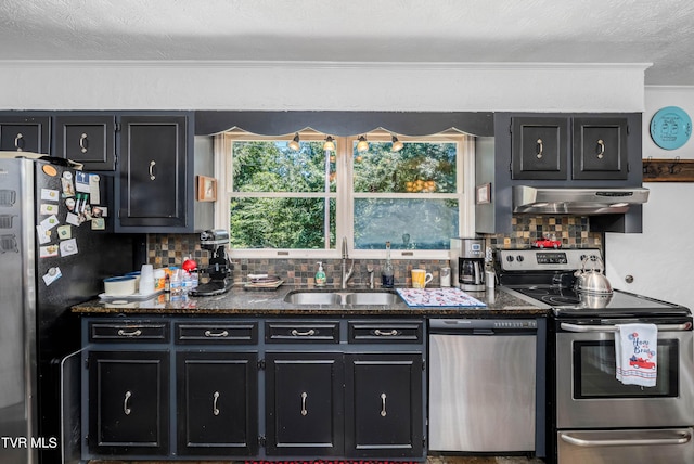 kitchen with sink, tasteful backsplash, dark stone counters, a textured ceiling, and appliances with stainless steel finishes