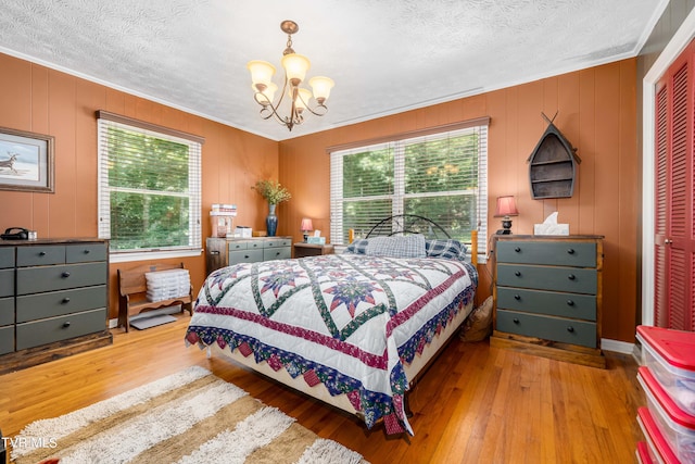 bedroom featuring a textured ceiling, light hardwood / wood-style floors, a closet, and ornamental molding