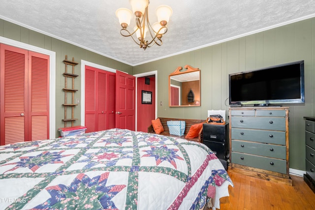 bedroom with a textured ceiling, light wood-type flooring, crown molding, and a notable chandelier