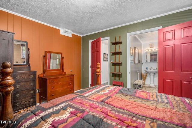 bedroom with ensuite bath, sink, a textured ceiling, wooden walls, and ornamental molding