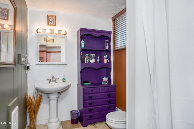 bathroom with tile patterned floors, toilet, ornamental molding, and a textured ceiling