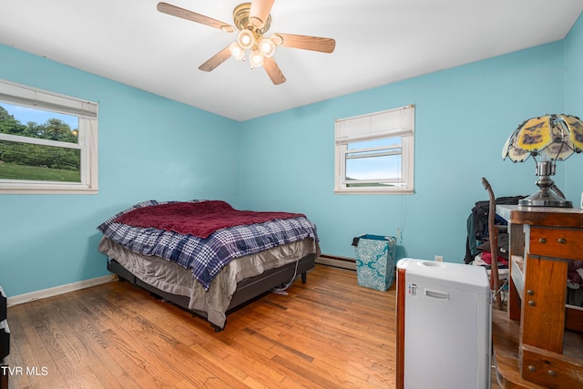 bedroom with ceiling fan, baseboard heating, and light hardwood / wood-style flooring