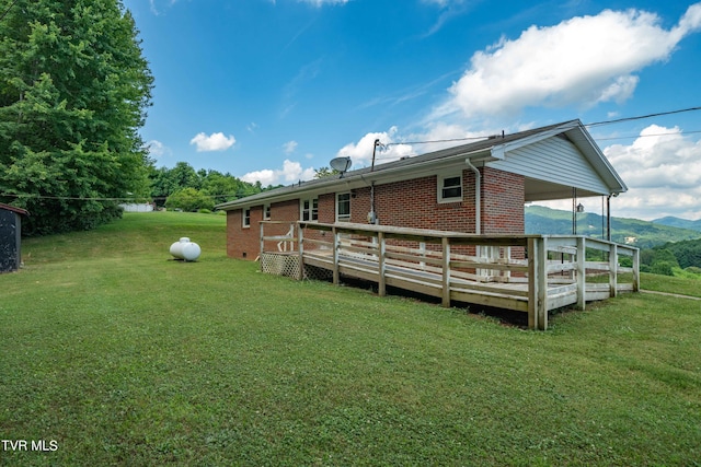 rear view of property with a deck with mountain view and a yard