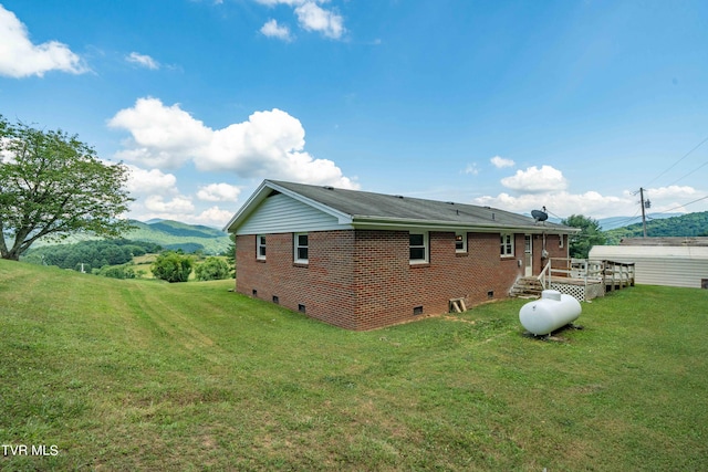 rear view of house with a deck with mountain view and a yard