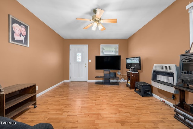 living room with ceiling fan, heating unit, and light hardwood / wood-style flooring