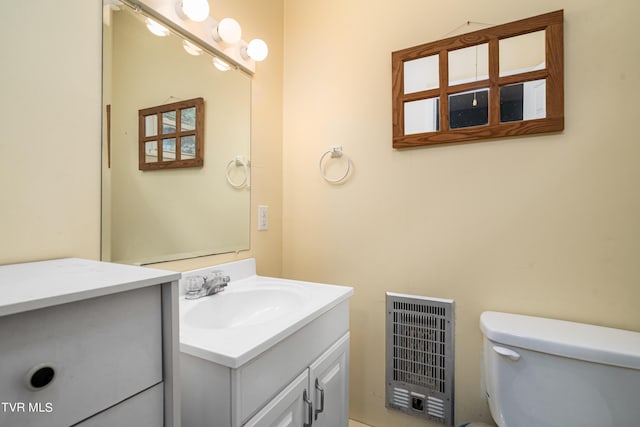 bathroom featuring heating unit, vanity, and toilet