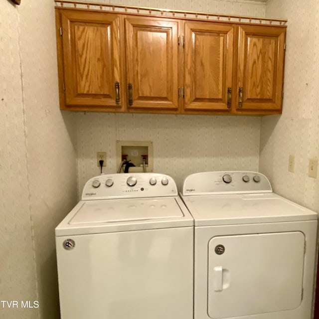 laundry area with separate washer and dryer and cabinets