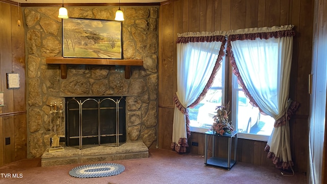 unfurnished living room featuring carpet floors, a stone fireplace, and wood walls