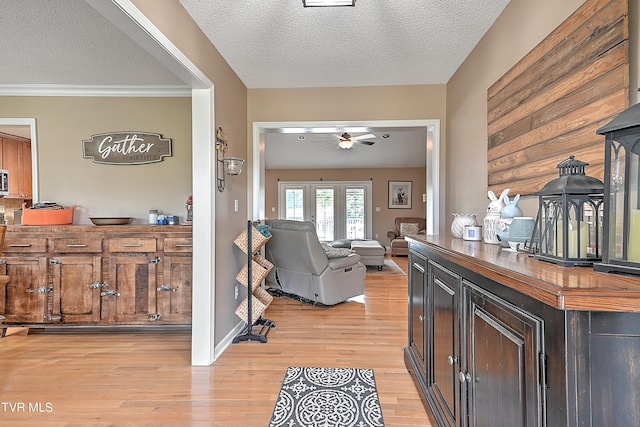 foyer with ceiling fan, a textured ceiling, light hardwood / wood-style flooring, and ornamental molding