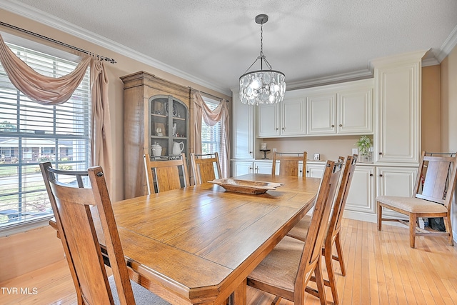 dining room with light hardwood / wood-style floors, ornamental molding, a chandelier, and plenty of natural light