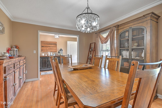 dining room featuring crown molding, a textured ceiling, light hardwood / wood-style flooring, and a notable chandelier