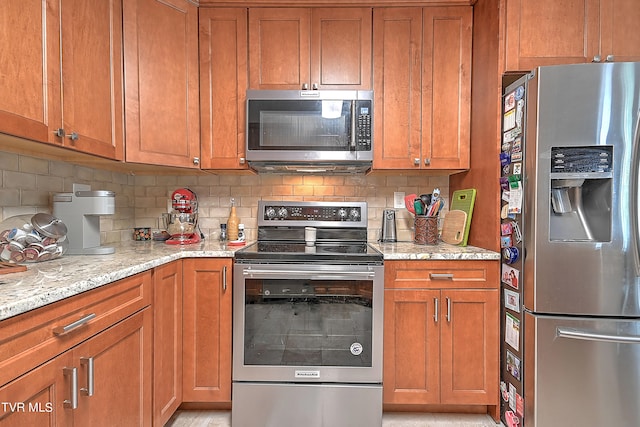 kitchen featuring decorative backsplash, light stone counters, and stainless steel appliances