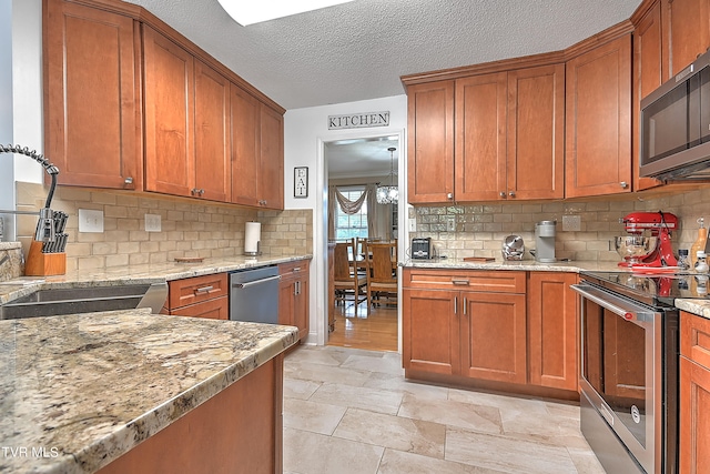 kitchen featuring stainless steel appliances, light hardwood / wood-style flooring, tasteful backsplash, and a textured ceiling