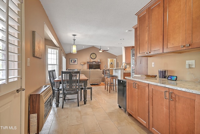 kitchen with light tile patterned flooring, ceiling fan, hanging light fixtures, light stone countertops, and lofted ceiling