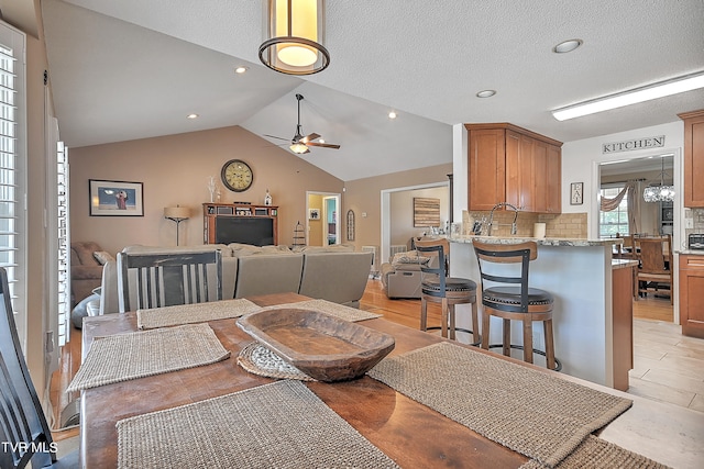 dining space with vaulted ceiling, ceiling fan, and light hardwood / wood-style floors