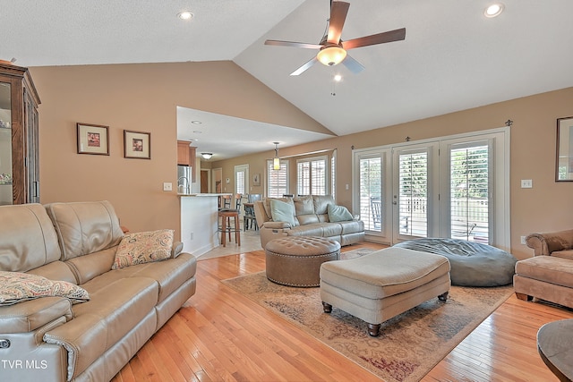 living room featuring light hardwood / wood-style flooring, ceiling fan, and vaulted ceiling