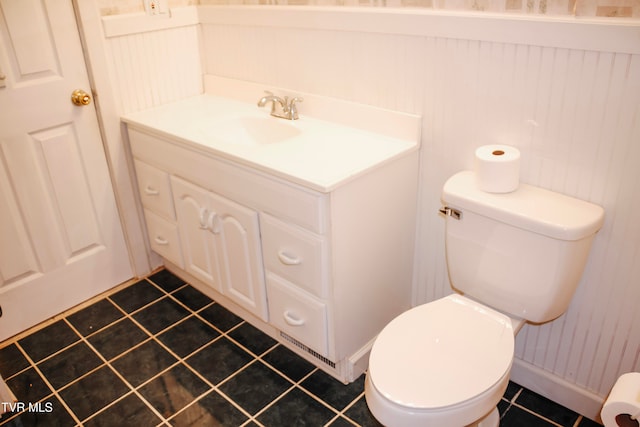 bathroom with tile patterned flooring, vanity, toilet, and wood walls