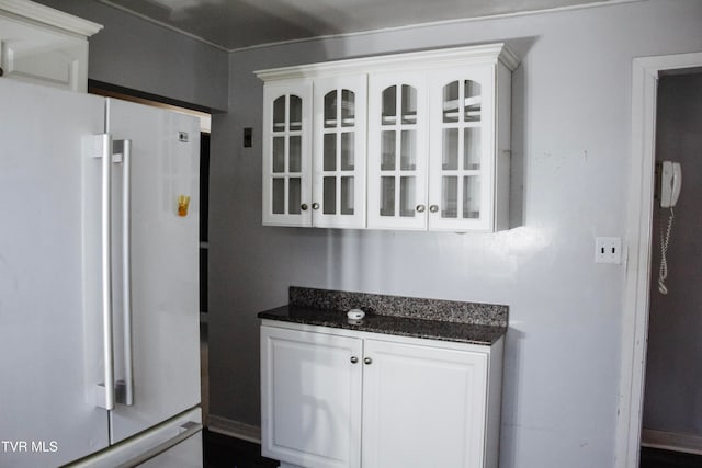 kitchen featuring white refrigerator, white cabinetry, and dark stone countertops