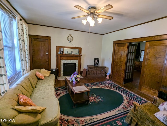 living room featuring hardwood / wood-style flooring, plenty of natural light, crown molding, and a stone fireplace