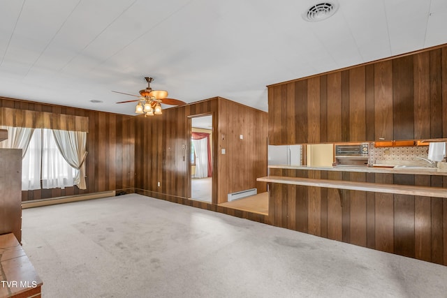 3054 Redbud Hwy, Honaker, VA 24260 - kitchen featuring a baseboard heating unit, carpet flooring, wooden walls, a ceiling fan, and decorative backsplash