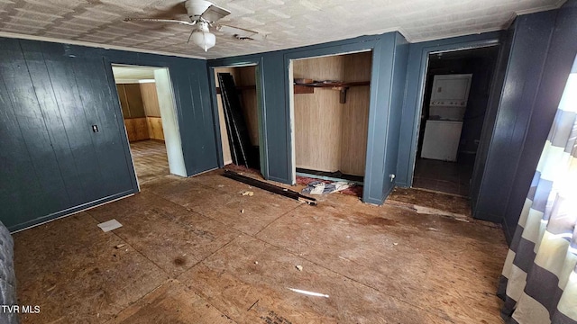 unfurnished bedroom featuring ceiling fan, multiple closets, and wooden walls