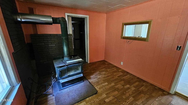 living room with a wood stove, dark hardwood / wood-style flooring, and wood walls