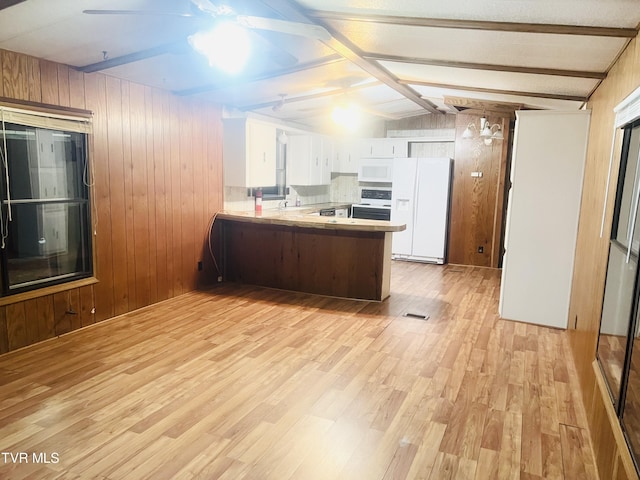 kitchen with vaulted ceiling with beams, kitchen peninsula, wood walls, white appliances, and white cabinets