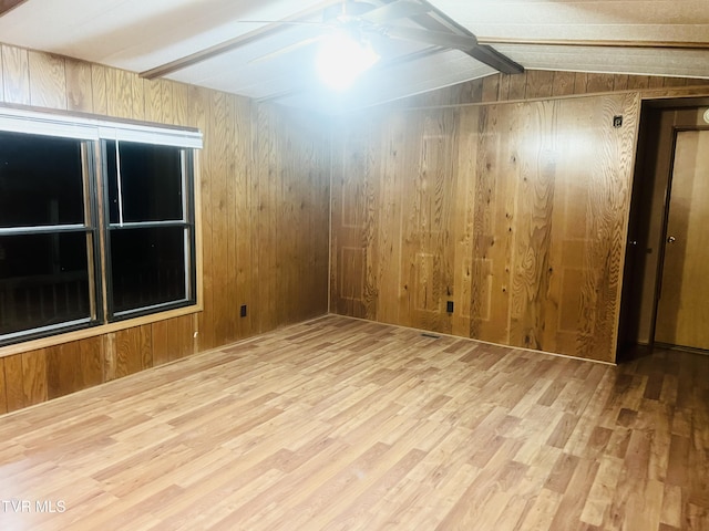 unfurnished room with hardwood / wood-style flooring, lofted ceiling, and wood walls