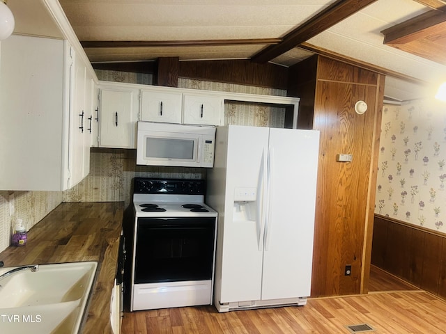 kitchen featuring wood walls, white appliances, white cabinets, sink, and vaulted ceiling with beams