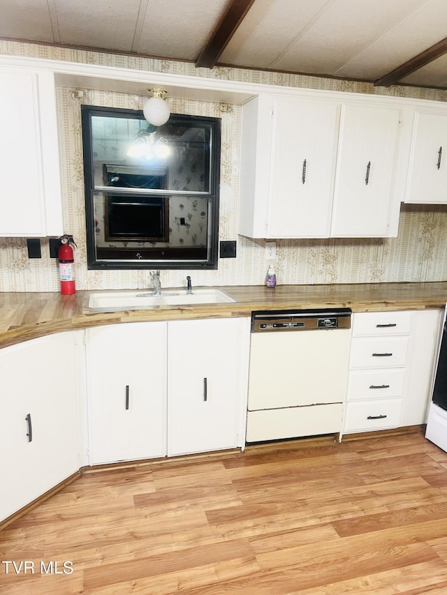 kitchen with wood counters, dishwasher, white cabinets, and sink