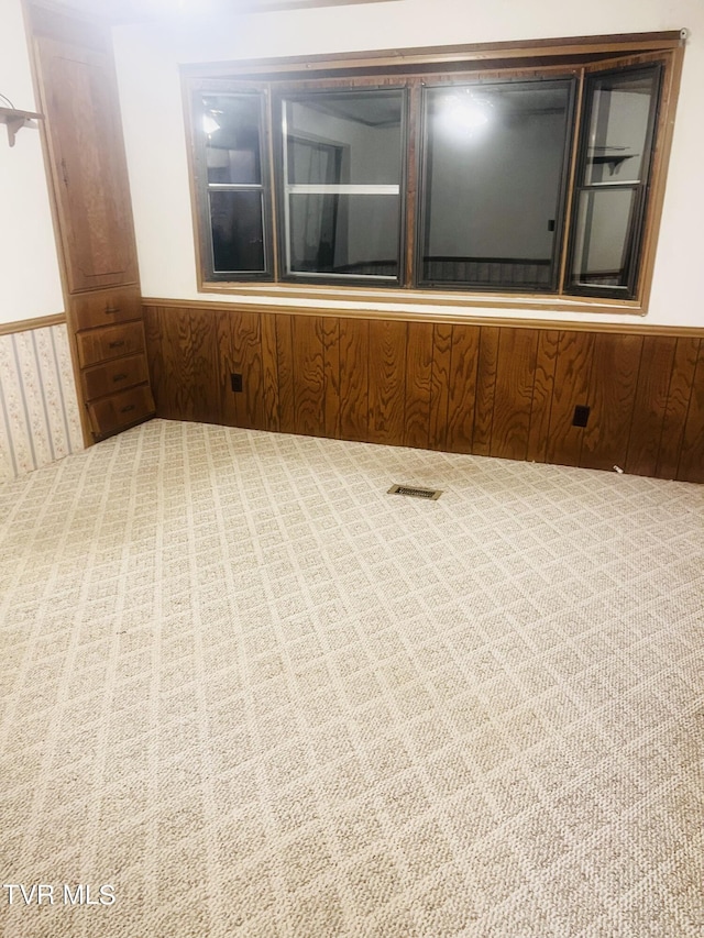 carpeted empty room with wood walls