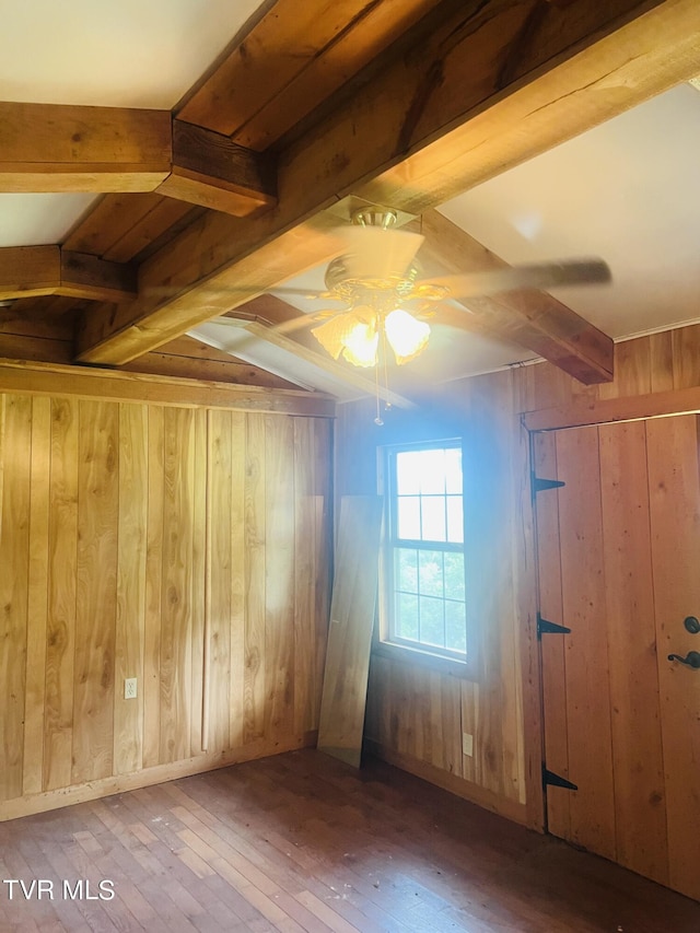 unfurnished room featuring hardwood / wood-style floors, ceiling fan, and wood walls