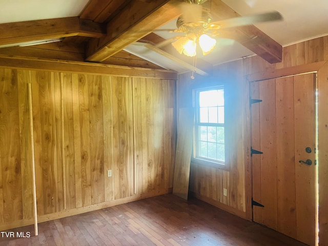 unfurnished room featuring beam ceiling, wood walls, ceiling fan, and hardwood / wood-style flooring