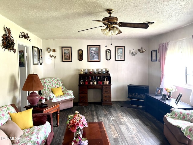 living room with a wood stove, dark hardwood / wood-style floors, ceiling fan, and a textured ceiling