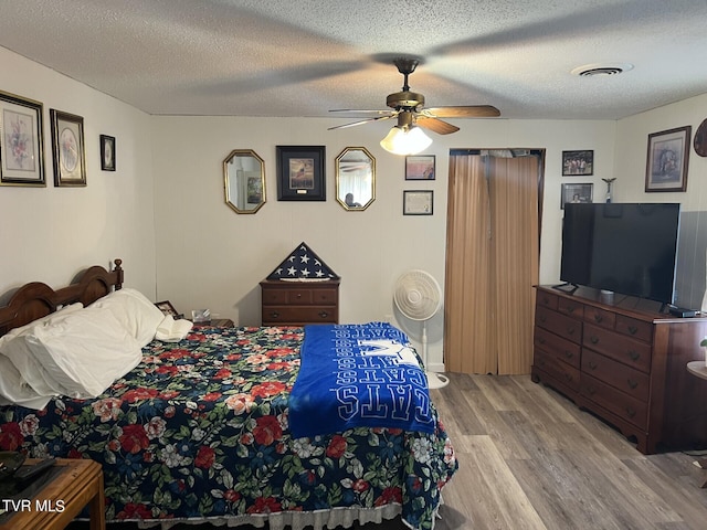 bedroom with light hardwood / wood-style flooring, a textured ceiling, and ceiling fan