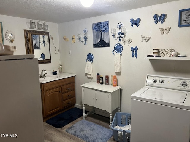 bathroom with a textured ceiling, vanity, washer / dryer, and hardwood / wood-style floors