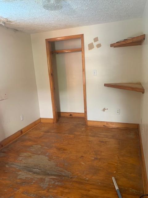 unfurnished bedroom with hardwood / wood-style flooring, a closet, and a textured ceiling