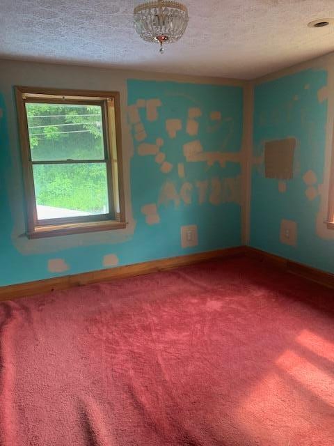 carpeted empty room featuring a textured ceiling