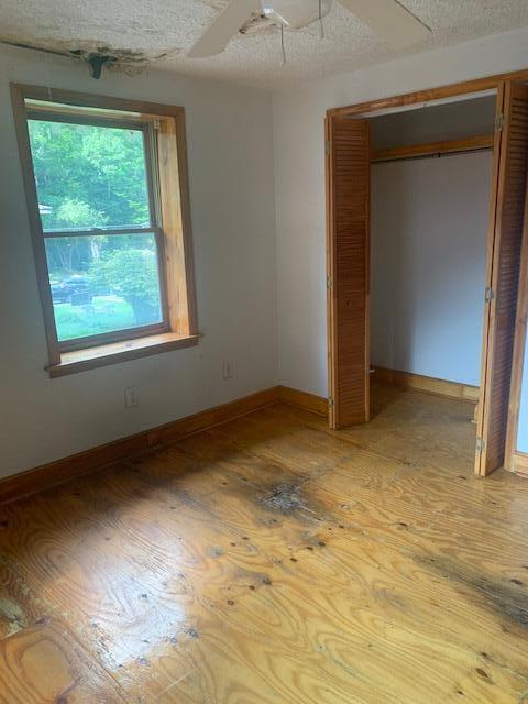 unfurnished bedroom with a textured ceiling, ceiling fan, and a closet